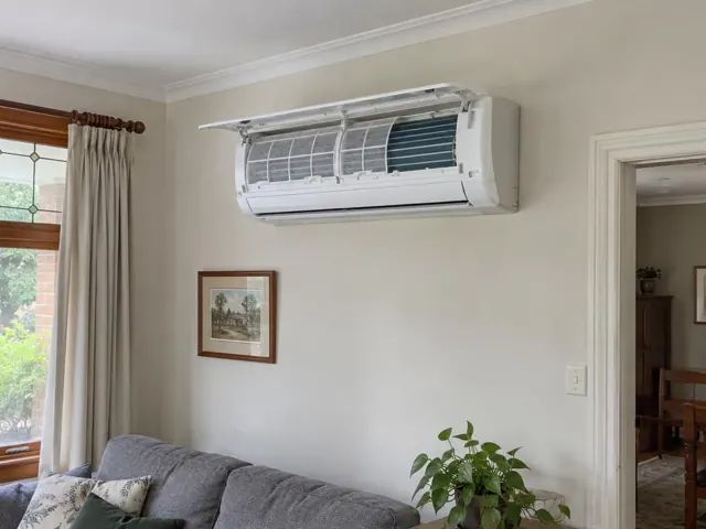 Clean split system indoor unit with open front panel and visible filters above a living room wall in Tea Tree Gully