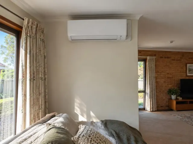 Wall-mounted split system above a lounge area in a carpeted brick home interior in Modbury Heights